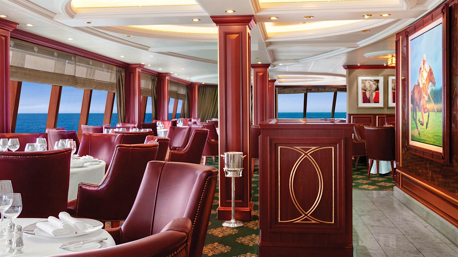 The wood-lined dining room at Oceania Cruise’s Polo Grill, with red leather seats and window views of the ocean